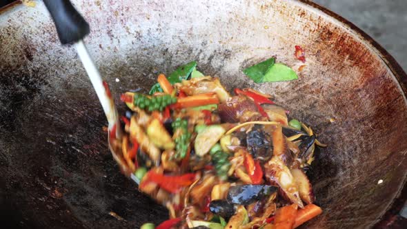 Cooking stir fried sea snail dish in wok with spatula, close-up