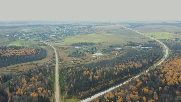 Aerial Flight Over the Road Between Fields and Autumn Trees in Yellow, Orange, Green Forest. Autumn