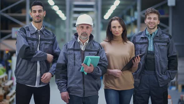 Four Men and Women Posing in Industrial Warehouse Looking at Camera with Confident Facial Expression