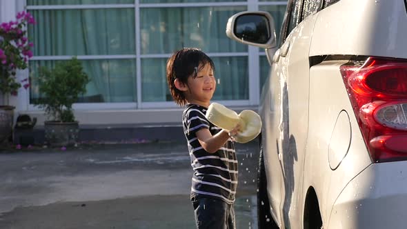 Asian Child Washing Car In The Garden On Summer Day Slow Motion