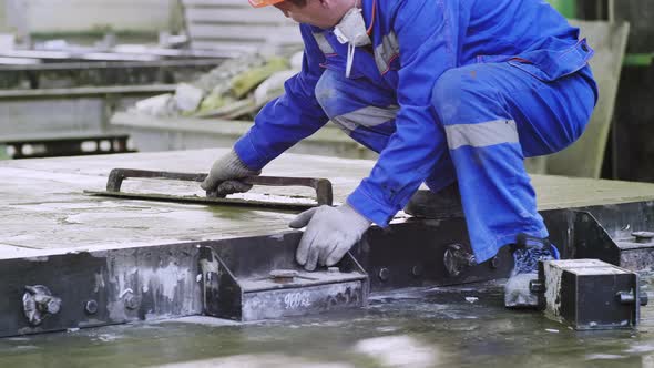 Factory worker leveling cement manually