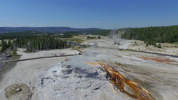 Camera circles a geyser as steam billows out and orange liquid streaming out