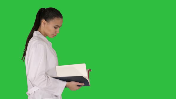 Attractive Medicine Student or Doctor with Notebook Walking and Reading on a Green Screen, Chroma