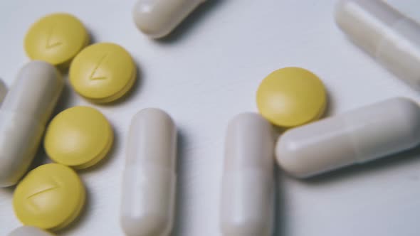White Capsules and Yellow Pills on Clean Light Background