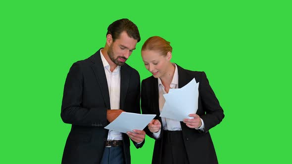 Two Young Business People Talking About Documents on a Green Screen Chroma Key