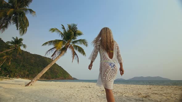 Back View of Woman in a White Tunic on Beach Near the Sea