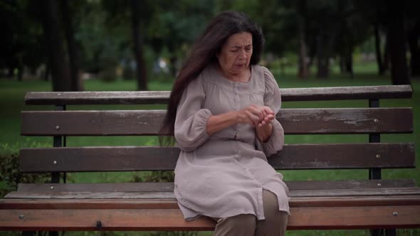 Anxious Caucasian Senior Woman Hurrying Taking Pill Painkiller Sitting on Bench in Park