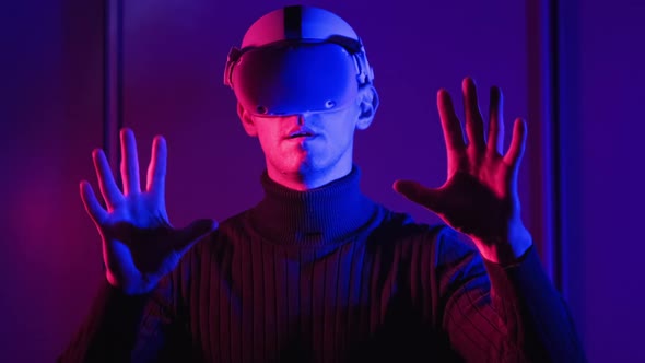 Young Man in VR Helmet Interacts with Virtual Reality Using His Hands