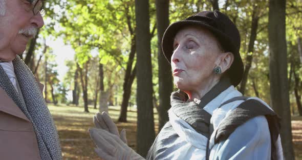 Portrait of Admiring Elderly Woman Talks To Her Man Remembers Something in Park