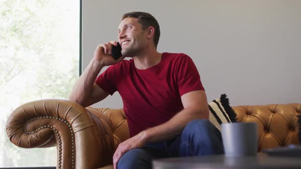 Happy caucasian man spending time at home and using smartphone