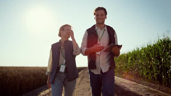 Smiling Farmers Walking Farmland on Sunny Day