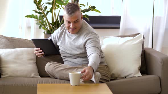 Man with Tablet Pc Sitting on Sofa at Home