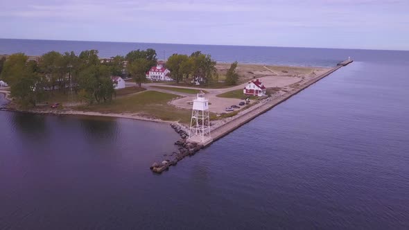 Wide aerial pan of lighthouse on pier and open water, Grand Marais, MI