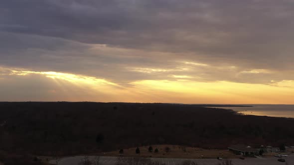 An aerial view over Montauk, NY during a golden sunset. The drone camera dolly in towards the sun, s