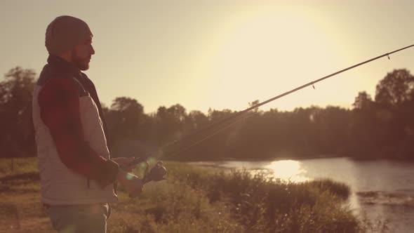 Fisherman with a spinning rod catching fish on a river.