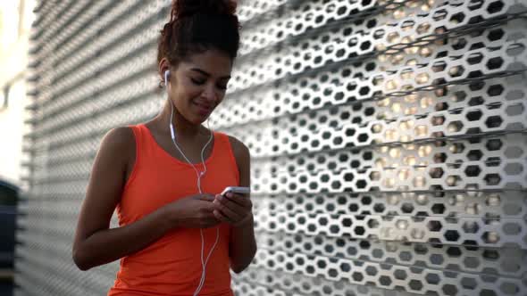 in Slow Motion Gorgeous Slim American Girl with Tied Dark Hair in Topknot Wearing Orange Shirt