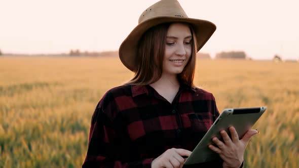 Female Agronomist Farmer with Portable Tablet Computer Using Application in Golden Wheat Field