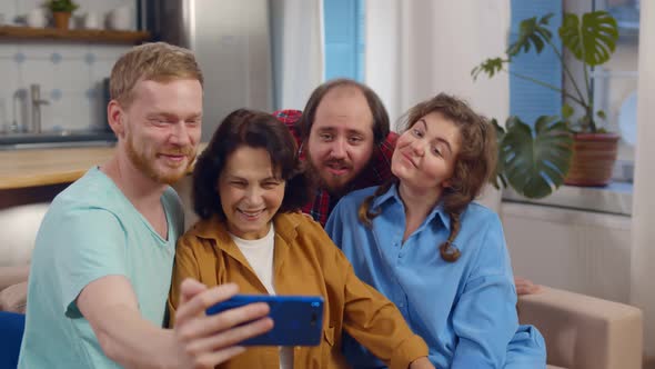 Senior Mother with Adult Children Sitting on Sofa Posing for Selfie on Mobile Phone