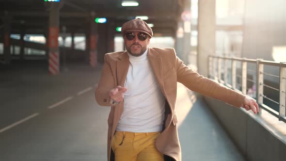 Cheerful and Happy Young Man with Beard Actively Dancing While Walking Down the Street on Sunset