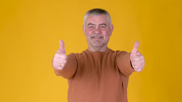 Cheerful Senior gray-haired man in white shirt showing thumb up