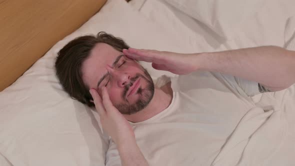 Casual Young Man Having Headache While Sleeping in Bed