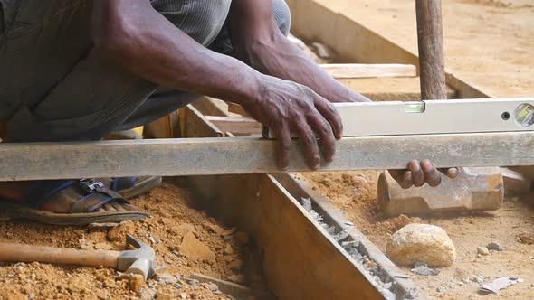 Male Indian Hands Checks Levels for Accuracy During Building Wooden Floor. Unrecognizable Local