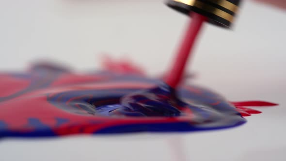 Female Hand Mixing Nail Polishes Together with Brush