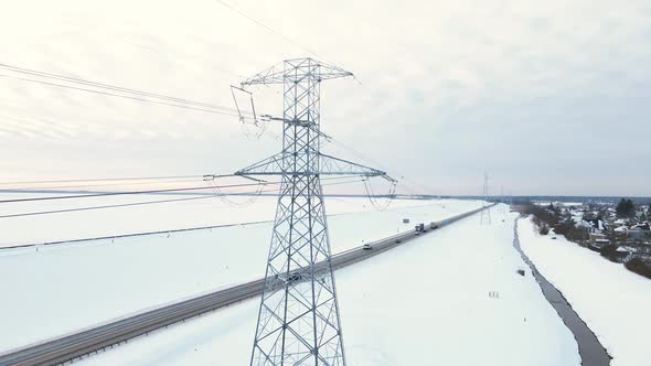 Power Lines with Towers Near Road with Traffic in Winter
