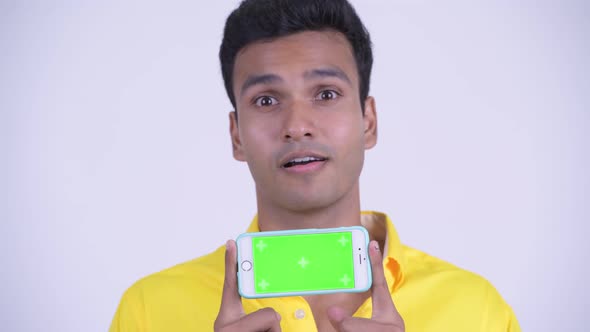 Face of Happy Young Indian Businessman Thinking While Showing Phone