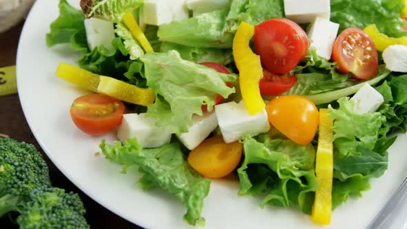 Vegetable salad with granola bar and measurement tape