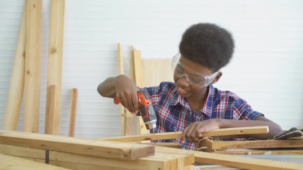 Little child with a drill in hands and help dad assembling furniture shelf with power screwdriver 