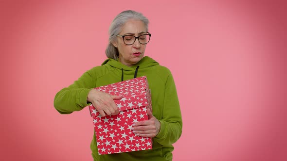 Elderly Granny Woman Opening Gift Box Expressing Disappointment Dislike Gesture to Awful Present