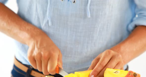 Smiling woman cutting mango on chopping board