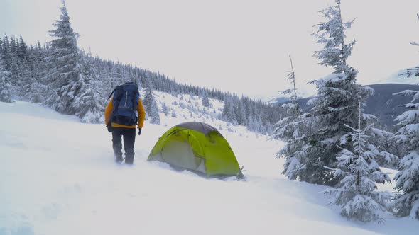 A Man with a Backpack Travels in the Winter Mountains