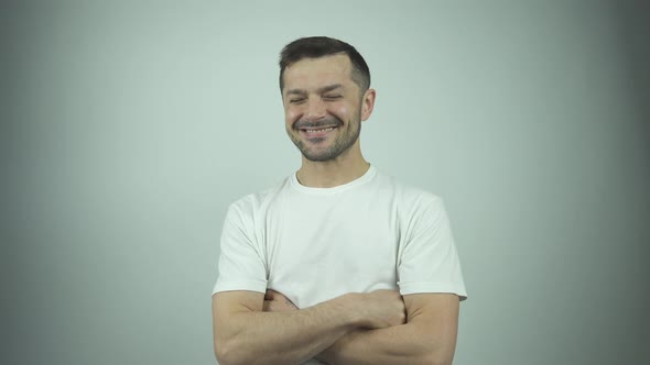 Cheerful Guy in T-shirt Laughs and Hides Face Behind Hand