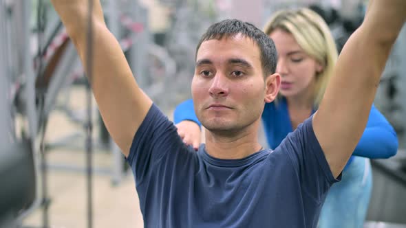 client of a gym diligently performs a row of the upper block on machine