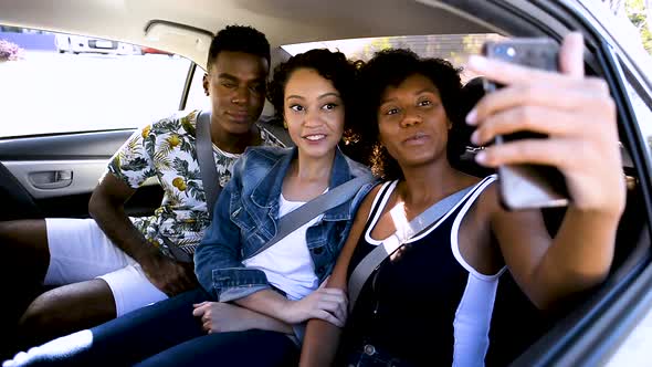 Three people in the car looking at their cell phone making selfie.