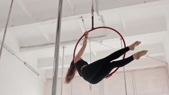 Gymnastic Woman Spinning on the Ring Under the Ceiling