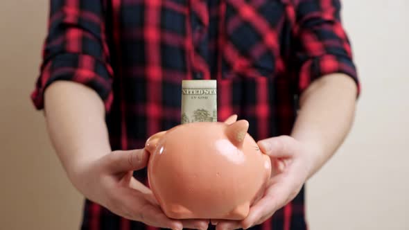 Woman Extends Slim Arms Holding Small Round Piggy Bank