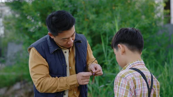Close View of the Asian Father Showing His Son How to Practice with Fishing Equipment Before Fishing