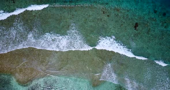 Daytime flying travel shot of a sunshine white sandy paradise beach and aqua blue water background 