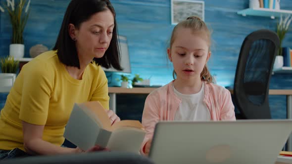 Pupil Using Laptop and Notebook for Homework with Help From Mother