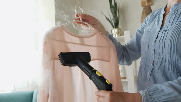 Woman is Steaming Steam Cleaner Shirt in a Room at Home
