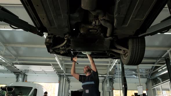 Auto mechanic working underneath car lifting machine at the garage, Auto repair 