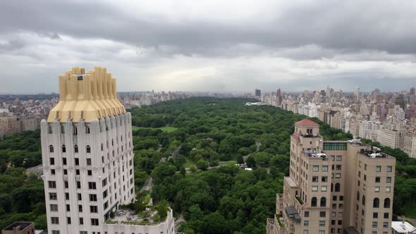 Aerial view flying in middle of buildings, towards the Central Park, in cloudy NYC, USA