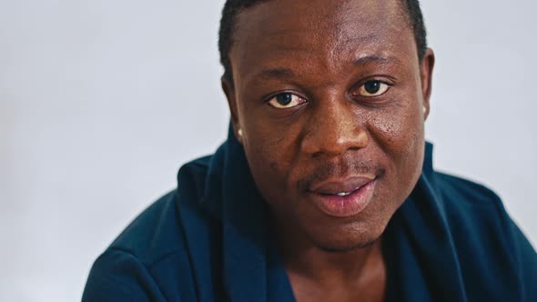 Happy African Guy Sitting on Bed Smiling at Camera Closeup