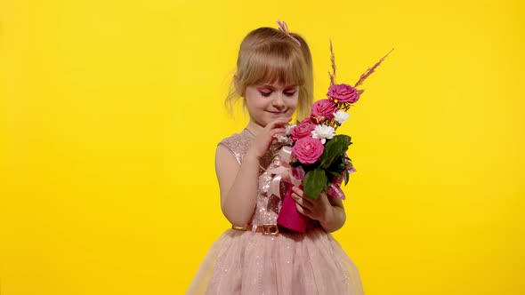 Little Child Girl with Fashion Makeup Standing with Bouquet of Flowers Isolated on Yellow Background