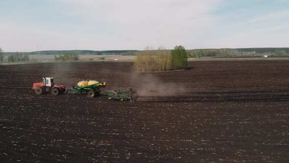 Process of Sowing Cereals and Other Crops. Drone View of a Modern Tractor Working on a Huge Field