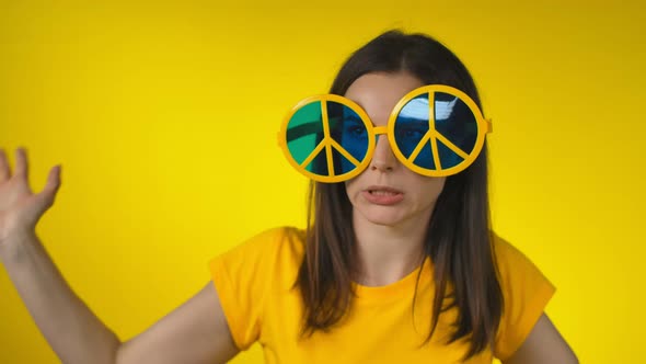 A Young Woman in Funny Yellow Hippie Sunglasses is Dancing and Fooling Around