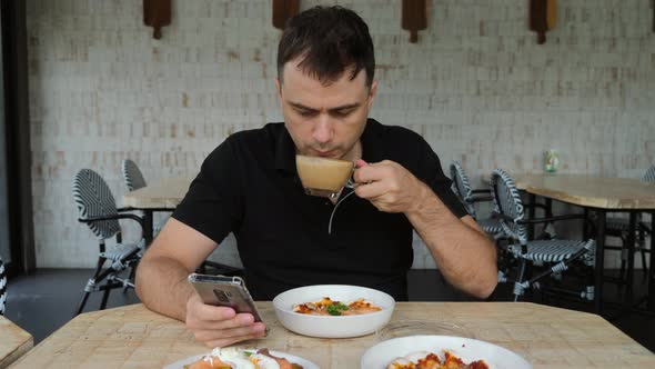 Man with Smartphone in Hand and Pizzas in Restaurant Drinking Coffee in Cafe